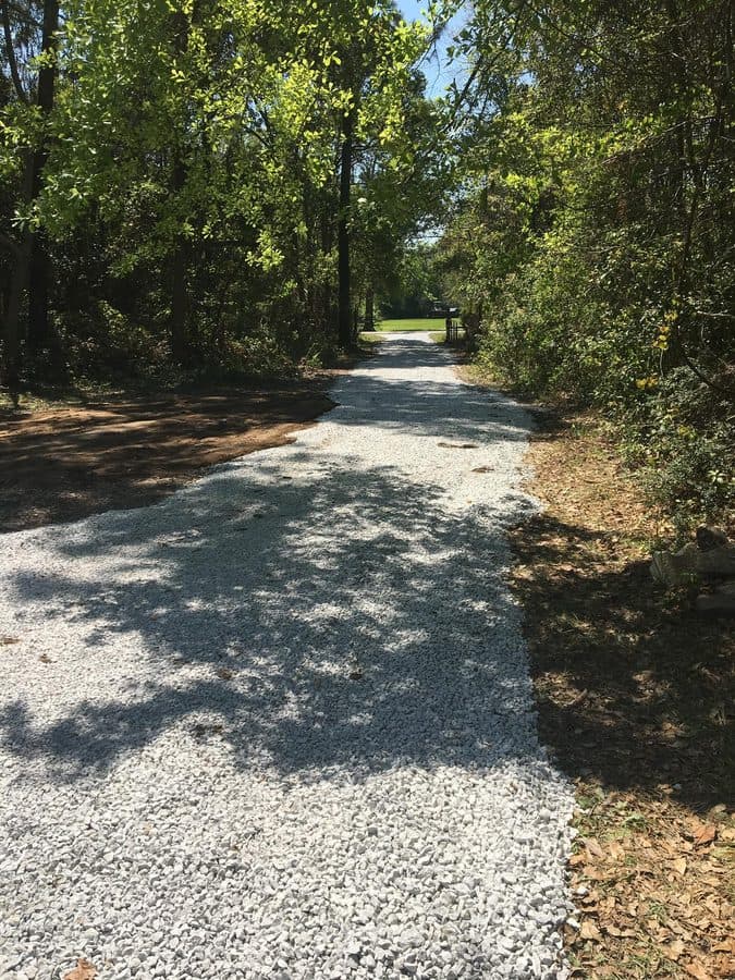 After gravel delivery on a wooded access road with a fresh gravel surface.